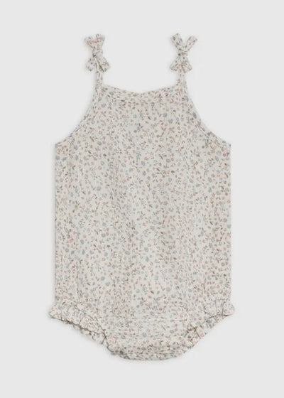 Adorable baby girl wearing a soft organic floral muslin romper outdoors